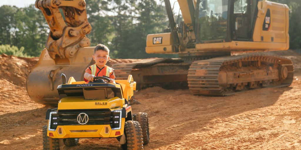 A child enjoys riding a toy vehicle on a construction site.