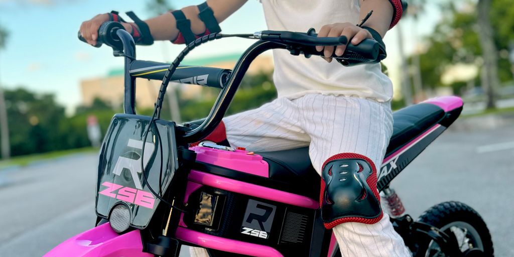 Child riding a pink electric bike, wearing safety gear.