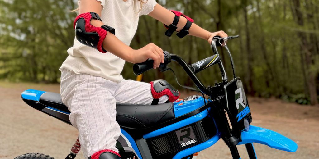 Child riding a blue electric bike, wearing safety gear outdoors.