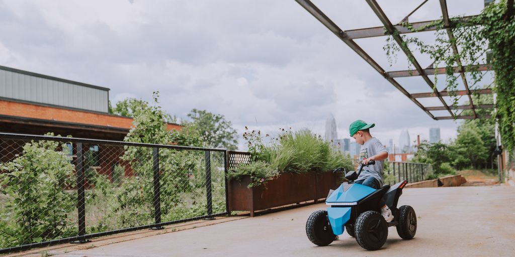 Child riding a small blue toy vehicle outdoors. Urban setting.
